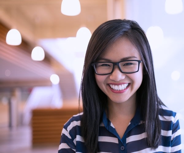 Female wearing glasses and striped shirt smiling in front of the camera.