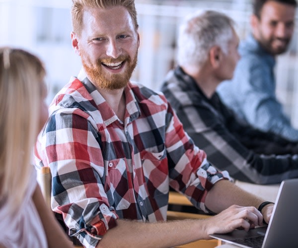 A man and a woman are having a fun conversation while doing work on the computer.