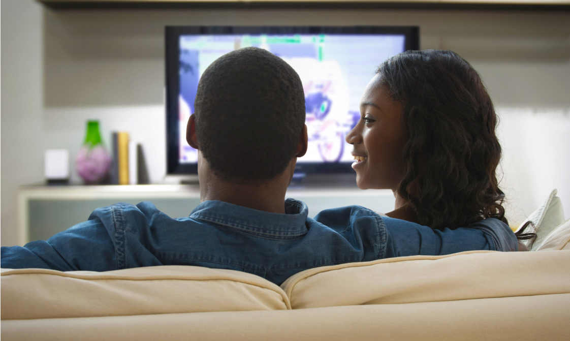 A couple is watching tv in their living room.