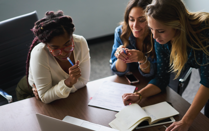 Three female coworkers are reviewing work order information in a meeting