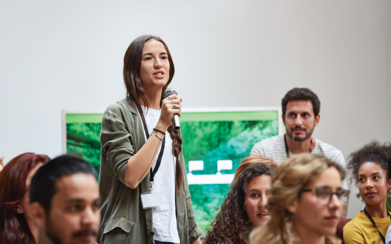 A female employee is interacting with coworkers in a town hall meeting