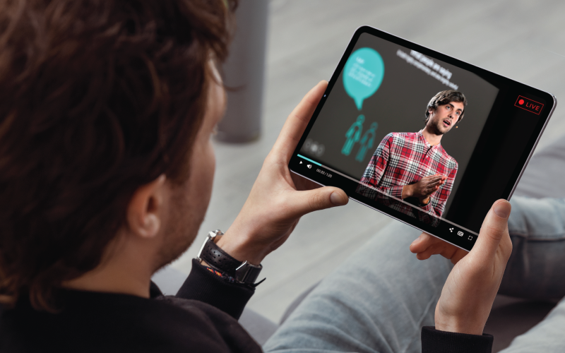 A man is watching a live work presentation video stream on a tablet